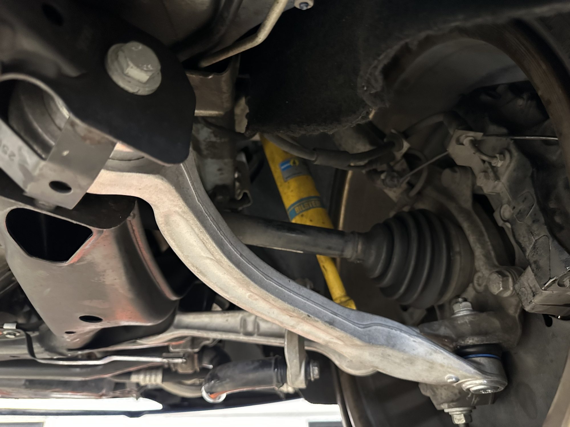 Close-up of front lower control arm, CV axle, and Bilstein shock